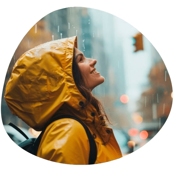 Chica sonriendo con chubasquero bajo la lluvia